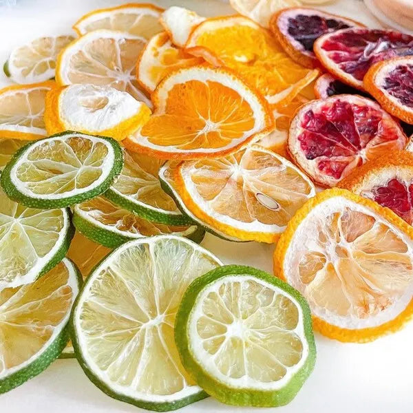 Assorted dried citrus wheels - lime, lemon, and orange - stacked on a white background